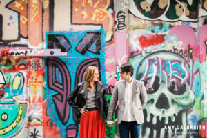 couple looking at each other in front of graffiti wall