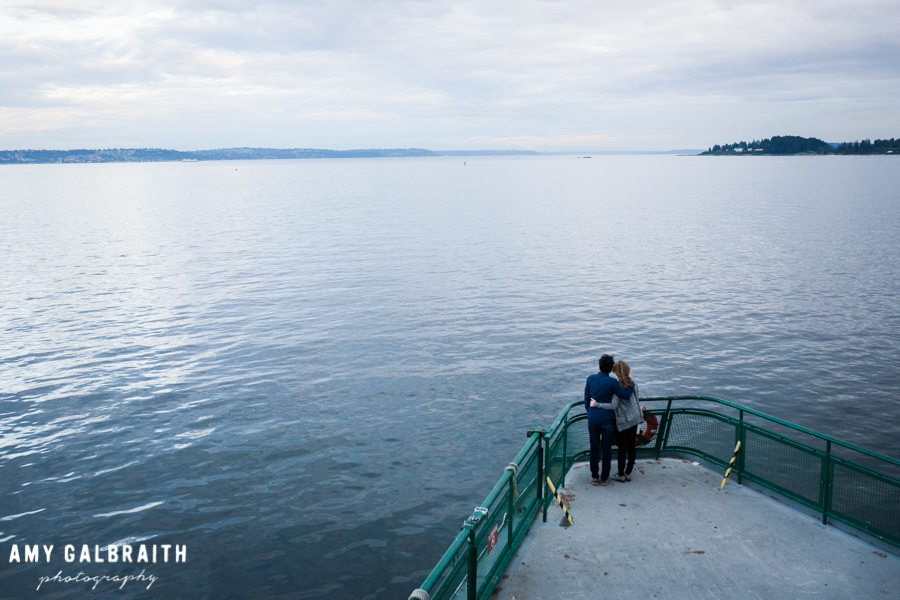 couple embracing while looking at a view of puget sound from a ferry