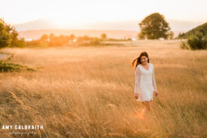 high school senior in tall grass with white dress at sunset in seattle
