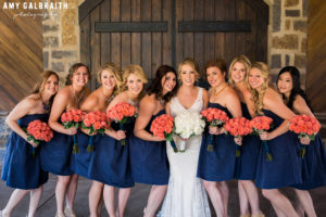 bridesmaids in navy dresses with coral bouquets