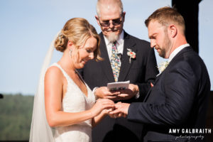 bride putting on her groom's wedding band during wedding ceremony