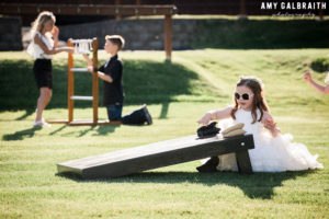 flower girl playing with corn hole set at wedding reception