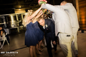 wedding party holding their arms up football style for bride and groom to walk through