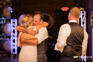 father of the groom hugging bride at wedding reception