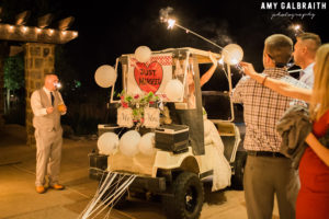 bride and groom riding away in a just married golf cart