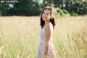 high school senior in floral print grass in a field of tall grass