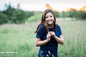 high school senior wearing blue t-shirt dress in tall grass at discovery park