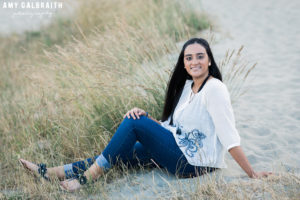 high school senior sitting on the beach in peasant shirt at discovery park