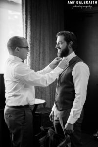 groomsman adjusting bow tie for groom