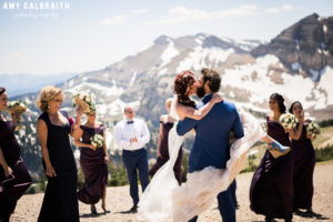 bride and groom kissing with wedding party in background