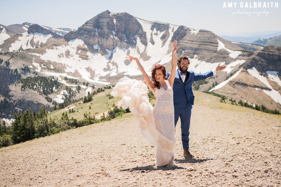 bride and groom cheering in front of cody peak in jackson hole