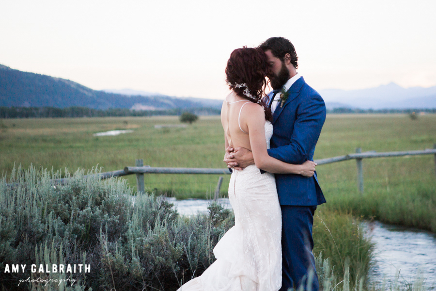 bride and groom embracing in field in teton village