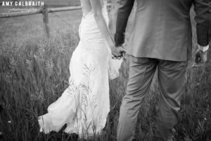 bride and groom holding hands in field at jackson hole