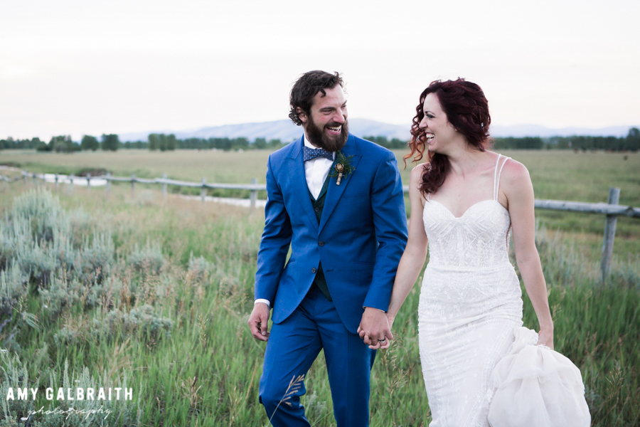 bride and groom walking through field in jackson hole