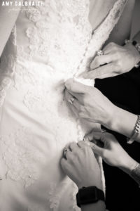 bride getting buttons on gown hooked before wedding