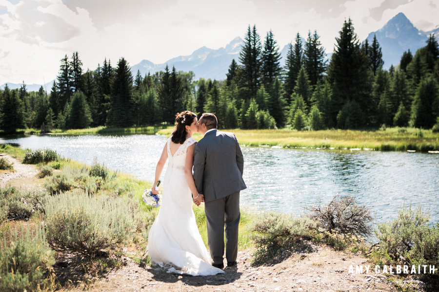 bride and groom kissing next to the snake river at schwabacher's landing