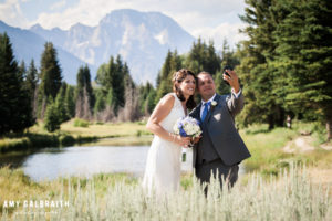 bride and groom taking a selfie in front of the tetons