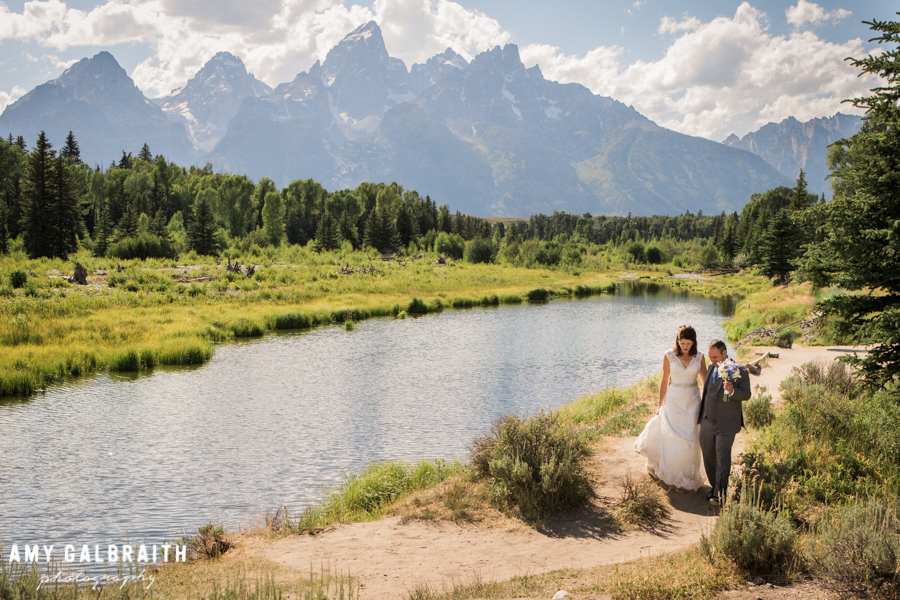 A bride and groom stroll along the Snake River at Schwabacher's Landing after their Grand Teton wedding in Jackson Hole