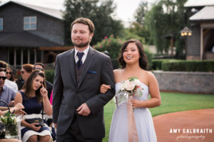 best man and maid of honor walking down aisle at hidden meadows wedding