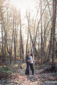 couple kissing among tall trees near snoqualmie river