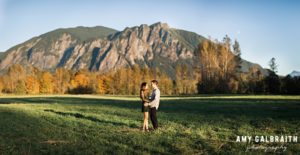 couple standing in field with views of mt si during snoqualmie engagement session