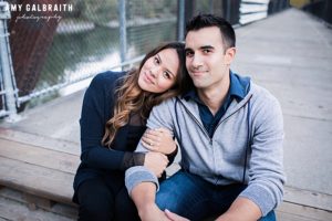 lindsey snuggles with scott while sitting on the bridge above the snoqualmie river