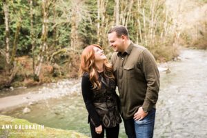 a couple laughs together along a river at Stevens Pass