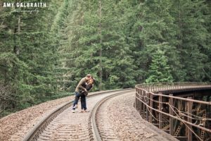 a couple dipping on the railroad tracks during their stevens pass engagement session
