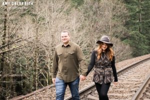 a couple walking along the railroad tracks during their engagement session at stevens pass