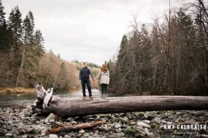 a couple standing on a large fallen log at stevens pass
