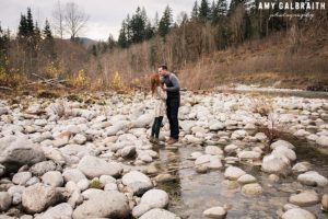 a couple kissing near the river at stevens pass during their engagement session