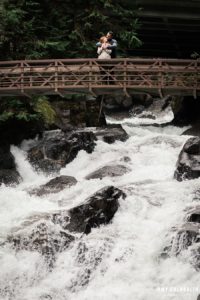 a couple standing on the bridge above angel falls at stevens pass