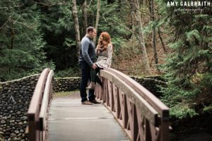 a couple chatting together on a bridge in the woods at stevens pass