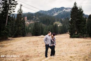 a couple standing in the field under cowboy mountain during their stevens pass engagement session