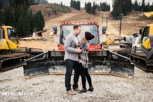 a couple standing near the snowcats during their fall engagement session at stevens pass