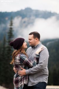 a couple standing amongst misty clouds during their stevens pass engagement session