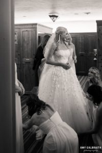 bridesmaids helping brides getting into wedding gown