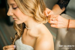 bride putting on necklace at the nines hotel in portland