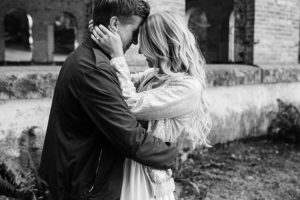 a couple gazes into each other eyes in front of a gorgeous brick building at manchester state park