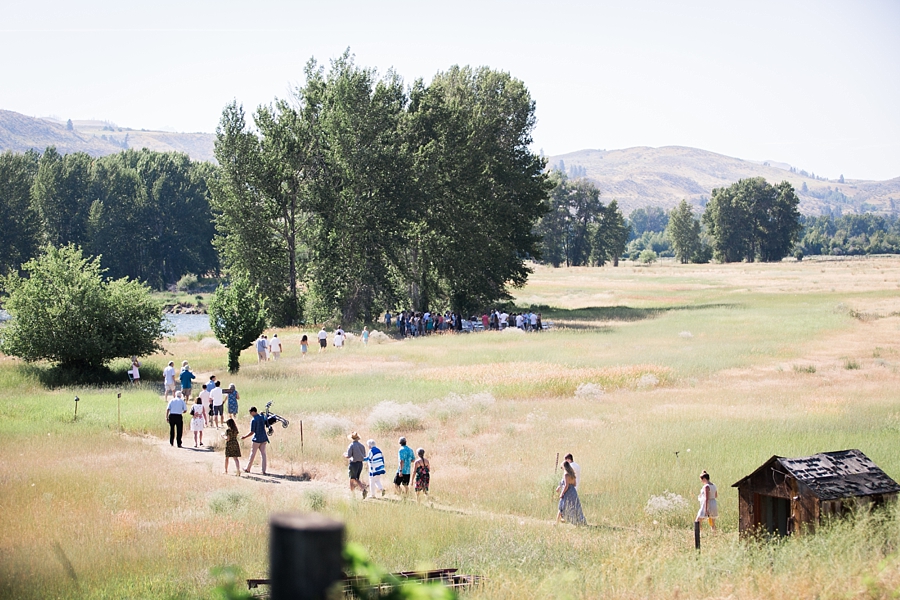 guests walk down a trail through a field to an outdoor ceremony in the mountains of the methow valley