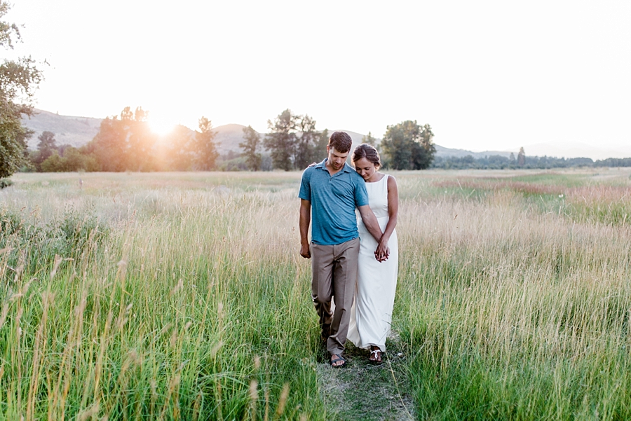 bride and groom hold hands while walking through a field outside of winthrop