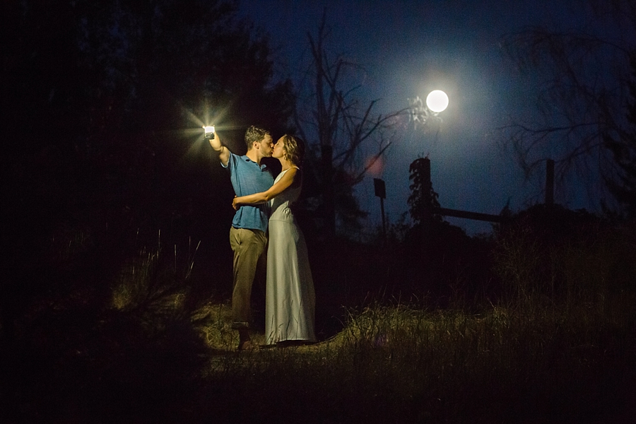 bride and groom kiss under the moonlight while holding a lantern