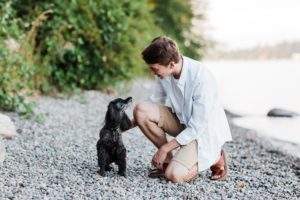 Raisbeck Aviation Senior Spencer poses with his dog Hobbs on a beach on Mercer Island