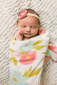 baby girl in floral swaddle with pink flower headband during lifestyle newborn session