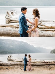 A bride wearing a floral pink gown on her wedding day shares a first look with her groom next to a mountain lake near Leavenworth