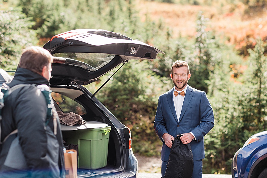A groom gets ready for his mountain elopement ceremony in the parking lot near a PCT trailhead