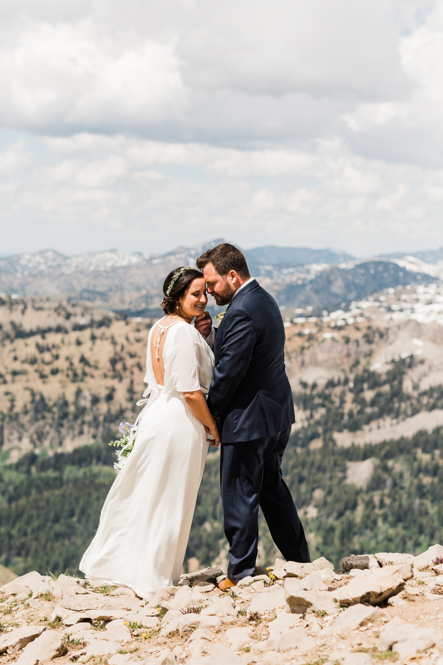 Bride and groom snuggle together on a mountaintop at their Jackson Hole wedding