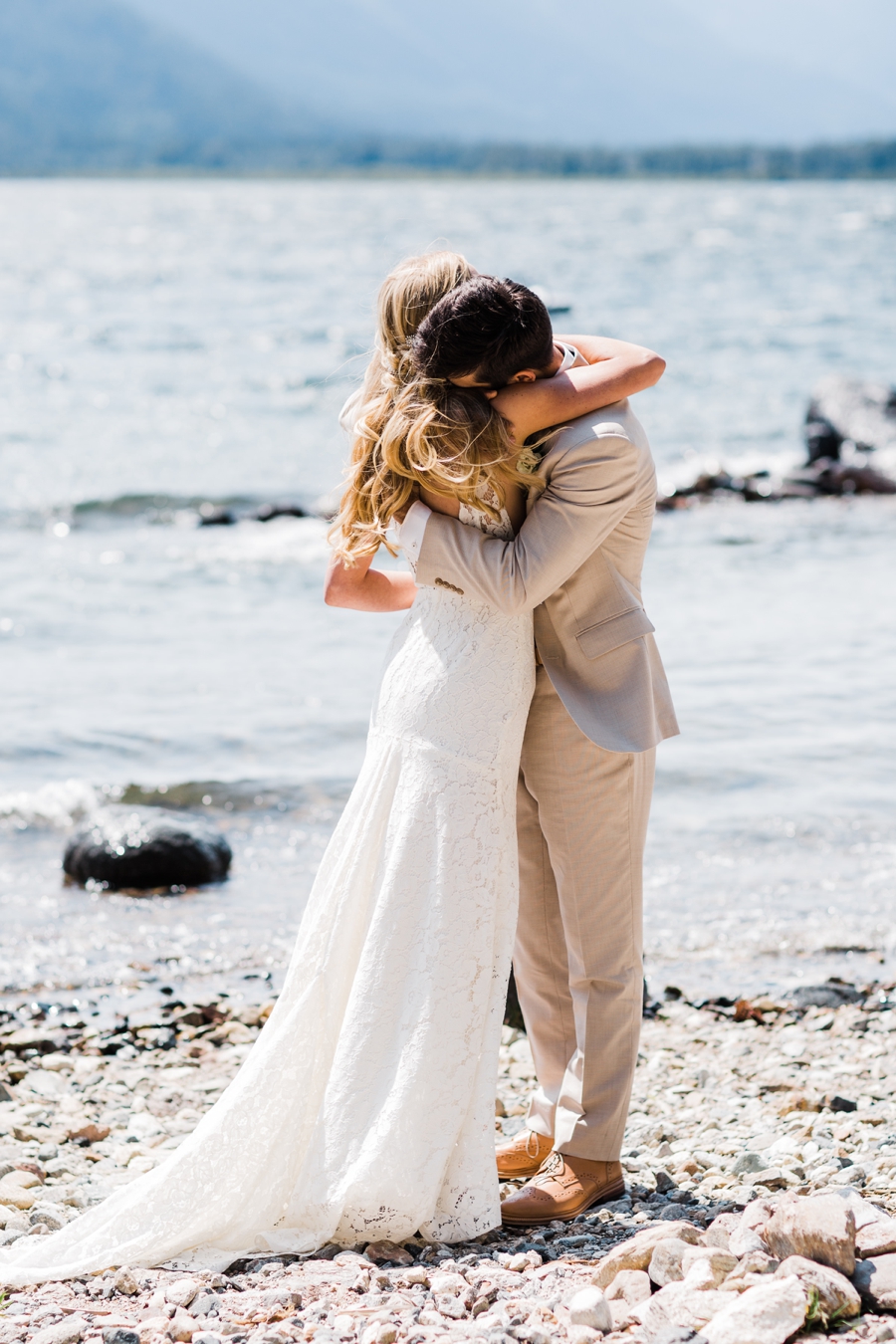 A bride and groom embrace near a mountain lake in Leavenowrth