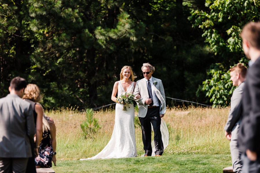 A bride walks down the aisle with her dad at Brown Family Homestead in Leavenworth