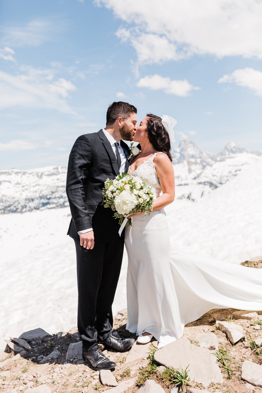 A bride and groom kiss on top of the snowy mountain for their Grand Targhee Wedding